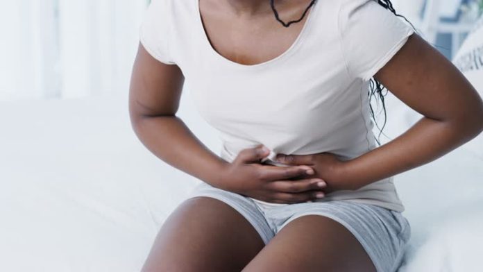 4k video footage of an unrecognisable woman experiencing stomach pain at home